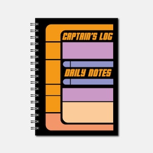May include: A black spiral-bound notebook with a design featuring orange, purple, and peach rectangles. The text "CAPTAIN'S LOG" and "DAILY NOTES" are displayed in a retro font. The notebook has a logo in the bottom left corner.
