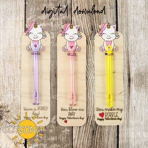 Puede incluir: Tres varitas de burbujas de madera para el Día de San Valentín con adornos de unicornio. Las varitas están decoradas con solución de burbujas rosa, amarilla y morada. El texto en las varitas dice: "Have a bubbly day! Happy Valentine's Day!" "You blow me away Happy Valentine's Day!" y "You make my bubble Happy Valentine's Day!"