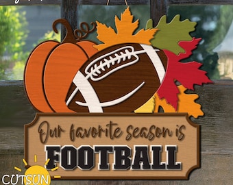 May include: A brown wooden sign with the text "Our favorite season is FOOTBALL" in black letters. The sign is decorated with a brown football, a pumpkin, and fall leaves.