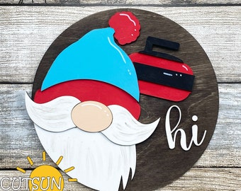 May include: A round wooden sign with a gnome face, a red and black curling stone, and the word "hi" in white script. The gnome has a blue hat with a red pom-pom and a white beard.
