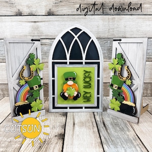 May include: A St. Patrick's Day-themed wooden decoration set. The set includes a central arched window design with a leprechaun holding a shamrock and the text "HEY LUCKY". Flanking the window are two wooden door panels with shamrocks, rainbows, and pots of gold.