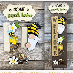 May include: A vertical porch sign with a bee gnome design. The sign says "Welcome" and has a honey bee and honeycomb design. The sign is made of wood and is painted in brown, yellow, black, white, and green colors. The sign is perfect for a front porch or entryway.