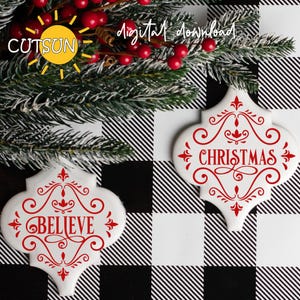 May include: Two white ceramic tiles with red lettering. One tile says "Believe" and the other says "Christmas". Both tiles have a decorative flourish design.