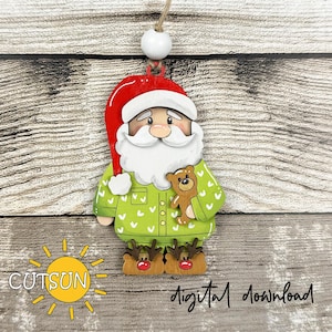 Könnte beinhalten: Weihnachtsbaumschmuck aus Holz mit Santa Claus in grüner Schlafanzug, der einen Teddybären hält. Santa trägt einen roten Hut und Rentierschuhe. Der Schmuck hat eine weiße Perle und eine Schnur zum Aufhängen. Der Text "CUTSUN" und "digital download" sind sichtbar.