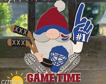 May include: A gnome wearing a red and blue hat, holding a hockey stick and a blue glove with the number "#1" on it. The gnome is standing in front of a wooden door with the words "GAME TIME" written below.