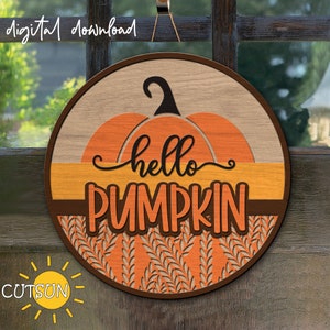 Könnte beinhalten: Ein rundes Holzschild mit einem Kürbisdesign und dem Text "hello pumpkin". Der Kürbis ist orange und braun mit einem Blatt-Stiel. Der Hintergrund ist eine braune Holzmaserung mit einem Muster aus orangefarbenen Blättern.