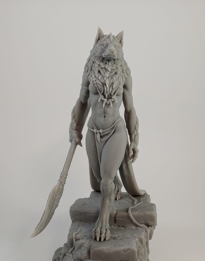 May include: A gray 3D printed figurine of a female wolf-like creature holding a spear. The creature is standing on a rocky base with vines.