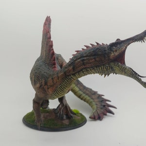 Puede incluir: Una miniatura detallada y pintada a mano de un dinosaurio Spinosaurus con un hocico largo y estrecho, una vela en la espalda y una cola larga y delgada. El dinosaurio est&aacute; pintado en tonos de marr&oacute;n, verde y rojo, y est&aacute; posado con la boca abierta en un rugido.