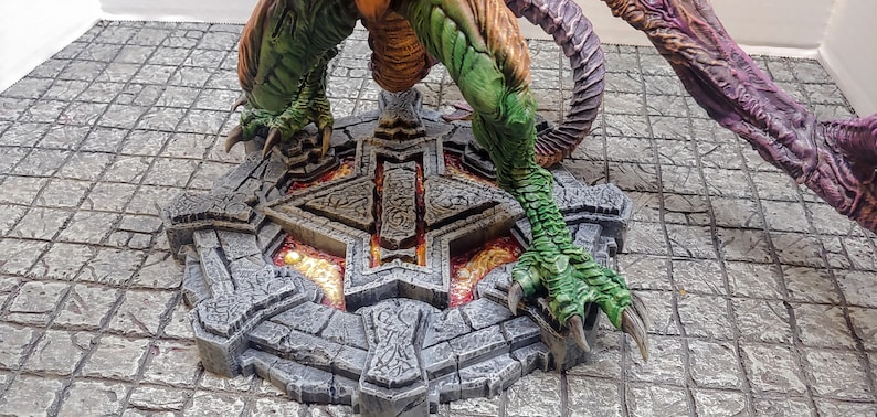 May include: A green and orange dragon figurine standing on a circular stone base with a glowing orange center. The base has intricate carvings and a star-shaped design.
