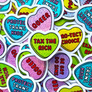 Pode incluir: Uma cole&ccedil;&atilde;o de autocolantes em forma de cora&ccedil;&atilde;o com fundos brilhantes e bordas brancas. Os autocolantes apresentam frases como "Protect Trans Kids", "Queer", "Tax the Rich" e "Be Gay Do Sins" em texto colorido.