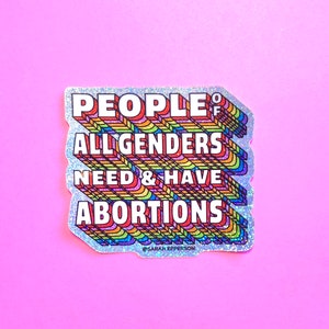 Pu&ograve; includere: Un adesivo glitter argentato con un design arcobaleno. L'adesivo dice "People of All Genders Need & Have Abortions" con il testo in un font arcobaleno. L'adesivo &egrave; su uno sfondo rosa.