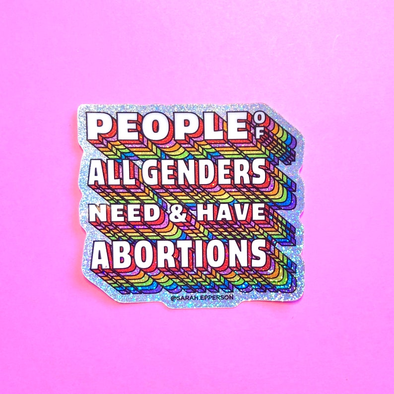 Pu&ograve; includere: Un adesivo glitter argentato con un design arcobaleno. L'adesivo dice "People of All Genders Need & Have Abortions" con il testo in un font arcobaleno. L'adesivo &egrave; su uno sfondo rosa.