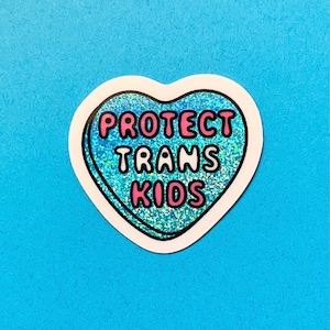 Pode incluir: Um autocolante em forma de cora&ccedil;&atilde;o com uma borda branca e um interior azul brilhante. O autocolante tem as palavras "PROTECT TRANS KIDS" em letras cor-de-rosa.
