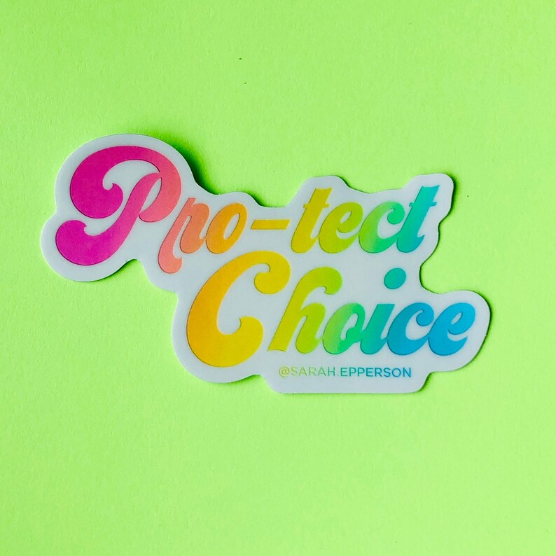 Pu&ograve; includere: Un adesivo bianco con il testo "Pro-tect Choice" in colori arcobaleno. Il testo &egrave; in un font stilizzato e l'adesivo ha un bordo bianco. Il testo "@SARAH_EPPERSON" &egrave; stampato in nero sotto il testo principale.