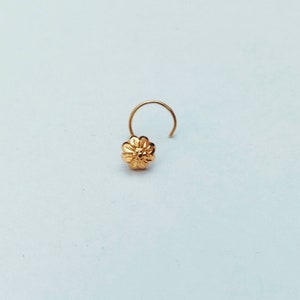Può includere: Un anello per il naso in oro con un design a fiore.