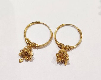 May include: A pair of gold hoop earrings with small, dangling charms. The charms are made of small, round beads and have a heart-shaped accent.
