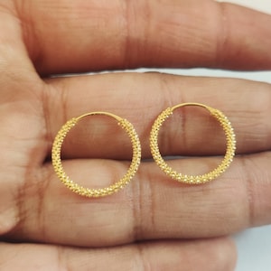Puede incluir: Un par de pendientes de aro de oro con una superficie texturizada.