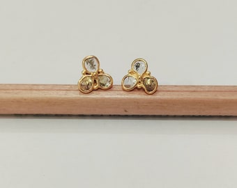 May include: A pair of gold earrings with three clear stones each, set in a clover shape.