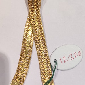 May include: A gold chain necklace with a textured, woven design. The chain is displayed on a white surface with a white oval tag that says "12,320".