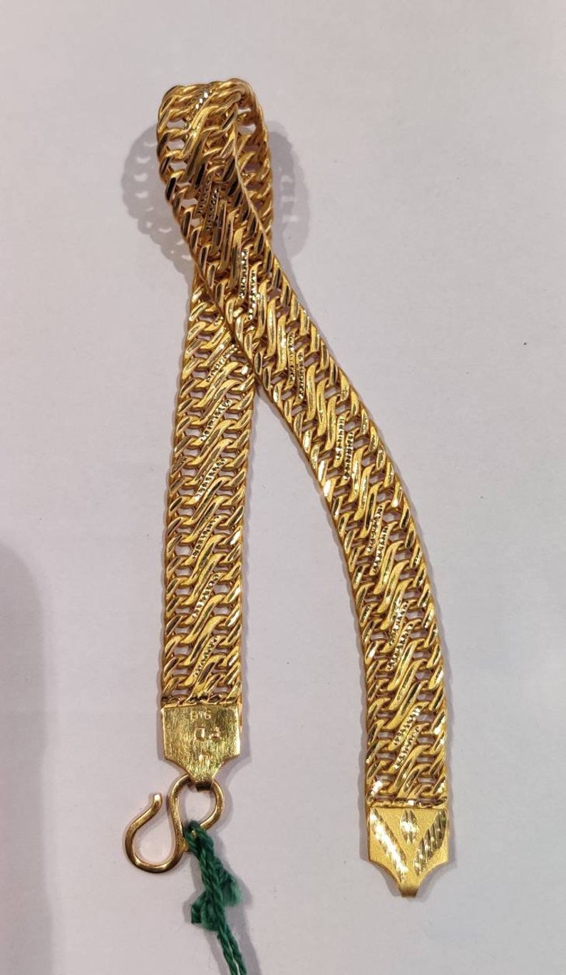 May include: A gold chain bracelet with a woven design. The bracelet has a hook clasp and is made of 18 karat gold.