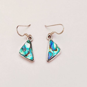 May include: A pair of silver earrings with triangular abalone shell pendants. The shells have a blue, green, and iridescent color pattern.