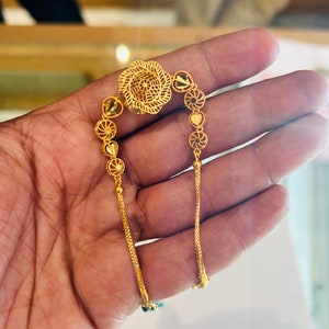 Pu&ograve; includere: Una collana a catena d'oro con un delicato design floreale e ciondoli a forma di cuore. La catena &egrave; realizzata con un motivo fine e intricato.