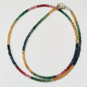Könnte beinhalten: Eine mehrfarbige Edelstein-Halskette mit einem silbernen Verschluss. Die Halskette besteht aus kleinen, runden Perlen in den Farben Blau, Grün, Gelb, Rosa und Rot.