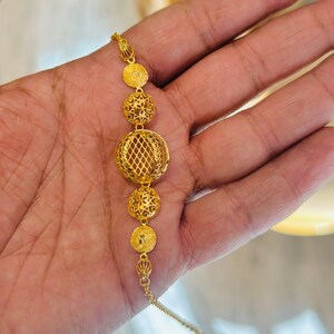 Pu&ograve; includere: Una collana d'oro con una catena delicata e cinque ciondoli rotondi traforati. I ciondoli sono finemente progettati con un motivo floreale.