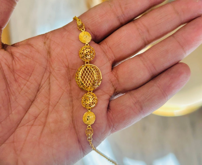 Pu&ograve; includere: Una collana d'oro con una catena delicata e cinque ciondoli rotondi traforati. I ciondoli sono finemente progettati con un motivo floreale.