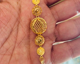 May include: A gold bracelet with a delicate chain and five round, openwork charms. The charms are intricately designed with floral and geometric patterns.