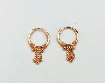 May include: A pair of gold hoop earrings with a dangling chain of small gold beads.