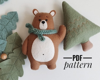 May include: A brown felt bear wearing a green scarf, standing next to a green felt Christmas tree. The text "PDF pattern" is written below the bear and tree.