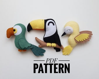 May include: A PDF pattern for sewing three felt bird toys: a green parrot, a black and white toucan, and a yellow bird with brown wings. The text "PDF PATTERN" is printed below the birds.