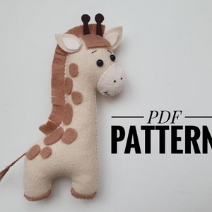 Könnte beinhalten: Eine beige Filz-Giraffe mit braunen Flecken und einer braunen Mähne. Die Giraffe hat schwarze Augen und eine braune Nase. Die Giraffe steht auf einer weißen Oberfläche. PDF PATTERN.
