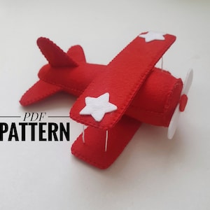 May include: A red felt airplane with white felt stars and a propeller. The airplane is a PDF pattern.
