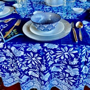 Peut inclure: Une table dress&eacute;e avec une nappe bleue et blanche &agrave; motifs floraux. L'ensemble comprend des assiettes blanches, des bols bleus &agrave; motifs, des verres transparents et des couverts dor&eacute;s. L'ambiance est &agrave; la fois classique et &eacute;l&eacute;gante.