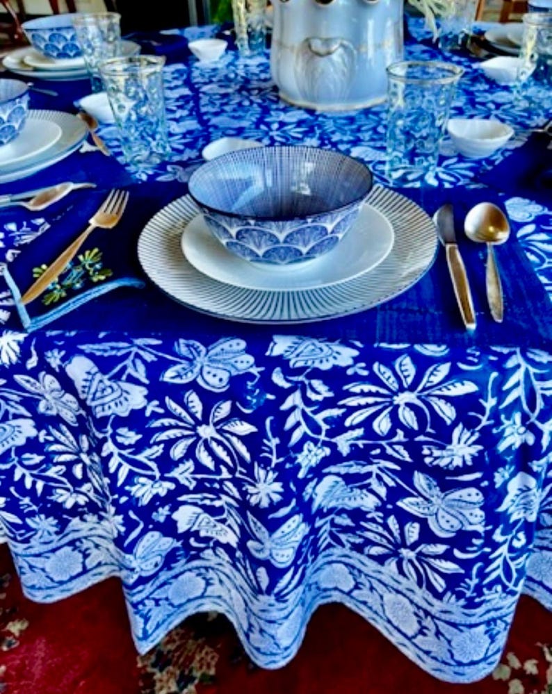 Peut inclure: Une table dress&eacute;e avec une nappe bleue et blanche &agrave; motifs floraux. L'ensemble comprend des assiettes blanches, des bols bleus &agrave; motifs, des verres transparents et des couverts dor&eacute;s. L'ambiance est &agrave; la fois classique et &eacute;l&eacute;gante.