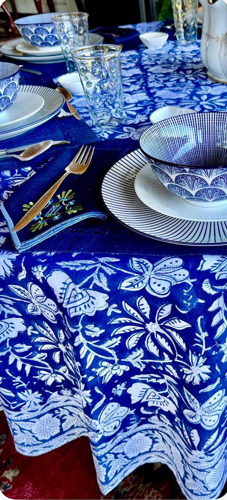 Peut inclure: Une table dress&eacute;e avec de la vaisselle &agrave; motifs bleus et blancs. La sc&egrave;ne comprend une nappe &agrave; motifs floraux, des assiettes, des bols et des couverts dor&eacute;s. L'esth&eacute;tique g&eacute;n&eacute;rale est un m&eacute;lange d'&eacute;l&eacute;gance et d'une touche de charme rustique.