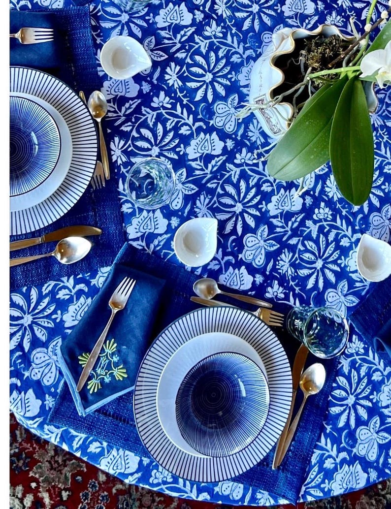 Peut inclure: Une table dress&eacute;e avec une nappe &agrave; motifs floraux bleus et blancs. L'ensemble comprend des assiettes &agrave; rayures blanches et bleues, de petits bols blancs, des couverts dor&eacute;s et des serviettes bleues. Des verres transparents sont &eacute;galement pr&eacute;sents.