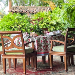Puede incluir: Una mesa redonda con un mantel floral y cuatro sillas. La mesa est&aacute; puesta con platos, vasos y servilletas. Las sillas son de madera y tienen un acabado marr&oacute;n claro.