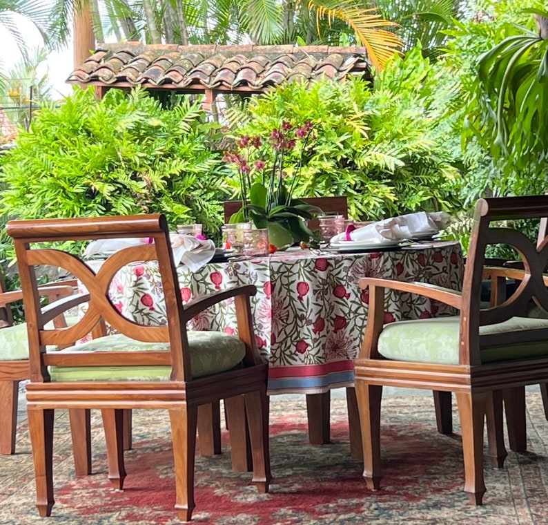 Puede incluir: Una mesa redonda con un mantel floral y cuatro sillas. La mesa est&aacute; puesta con platos, vasos y servilletas. Las sillas son de madera y tienen un acabado marr&oacute;n claro.