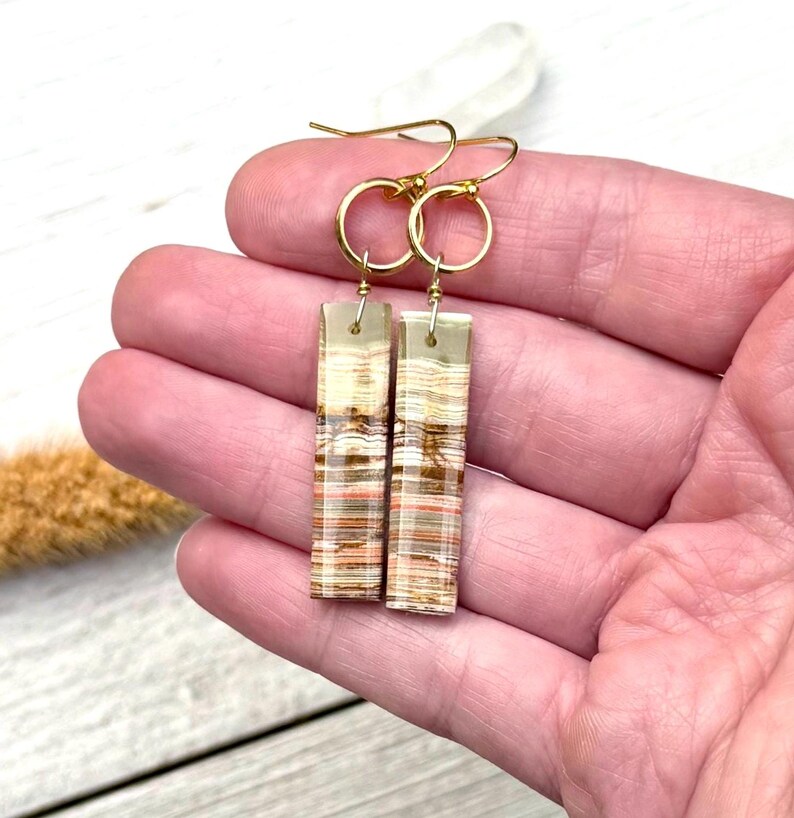Op de afbeelding: Een set van drie keramische mokken met een gespikkelde, matte afwerking. De mokken zijn in cr&egrave;me, lichtgrijs en donkergrijs. Elke mok heeft een eenvoudig, minimalistisch ontwerp en een afgeronde handgreep.