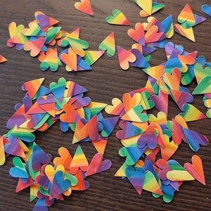 May include: A large pile of rainbow-colored heart-shaped confetti. The confetti is made of paper and has a variety of different rainbow patterns.
