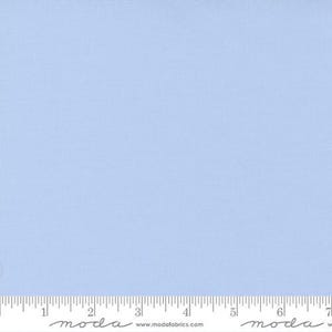 May include: A solid light blue fabric swatch with a ruler and the text "moda" printed on it.