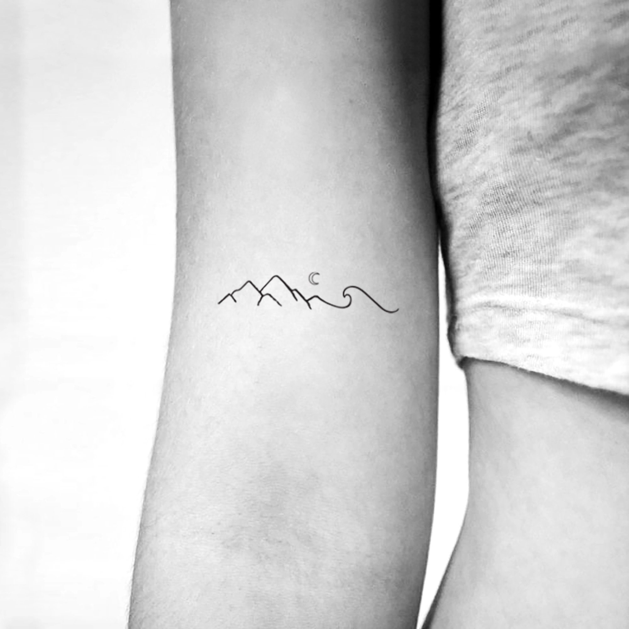 Minimalist mountain tattoo on the inner forearm