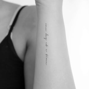 Pode incluir: Uma fotografia a preto e branco de um braço com uma tatuagem que diz "one day at a time".