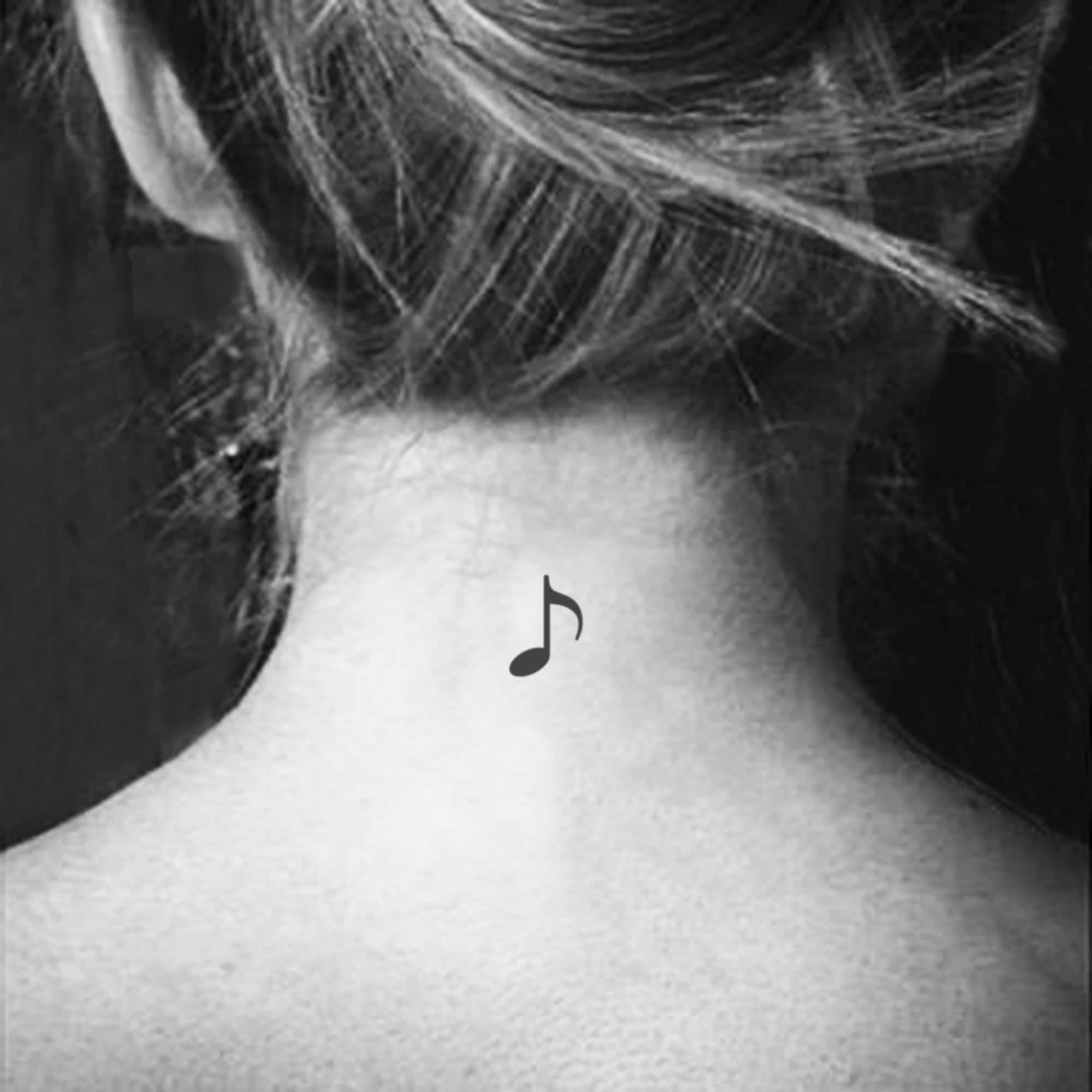 Minimalistic Saturn and music note tattoo located on