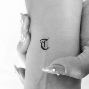 Tatuaje temporal de letra T gótica