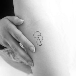 Könnte beinhalten: Ein Tattoo-Design in Schwarzweiß mit drei sich überlappenden Kreisen auf dem Arm einer Person.