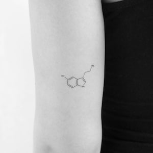 Pode incluir: Um desenho em preto e branco da estrutura química da serotonina, um neurotransmissor que desempenha um papel na regulação do humor, da felicidade e do sono.